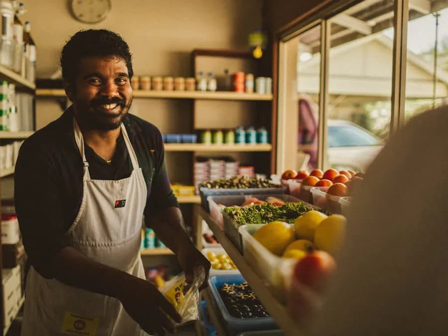 Comerciante sorrindo em seu mercadinho