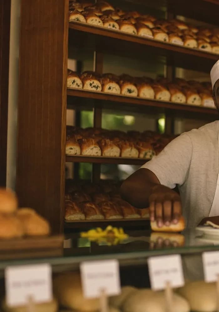 Padeiro organizando pães na vitrine